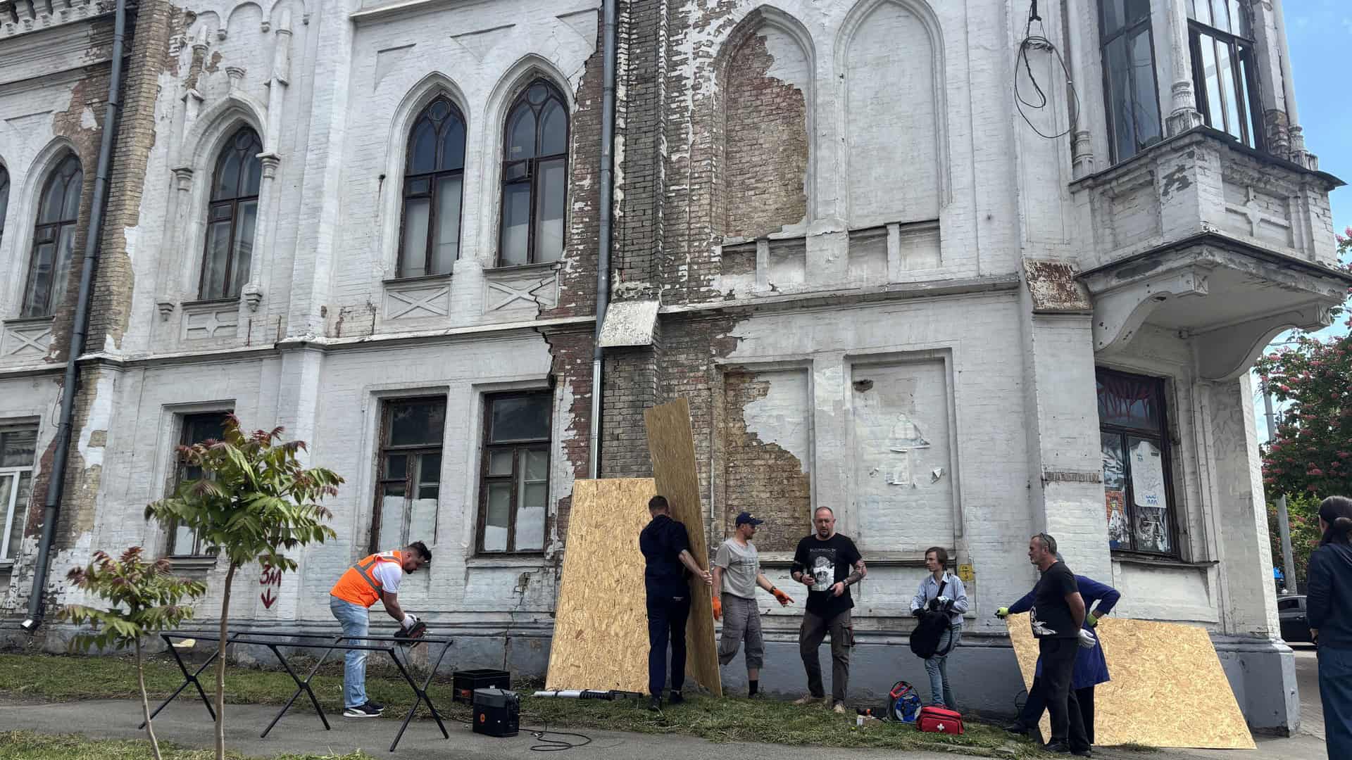 Волонтери і активісти під час толоки закривають пошкоджені вікна та прорізи OSB-плитами на фасаді Садиби Терещенків — пам'ятки архітектури у Києві