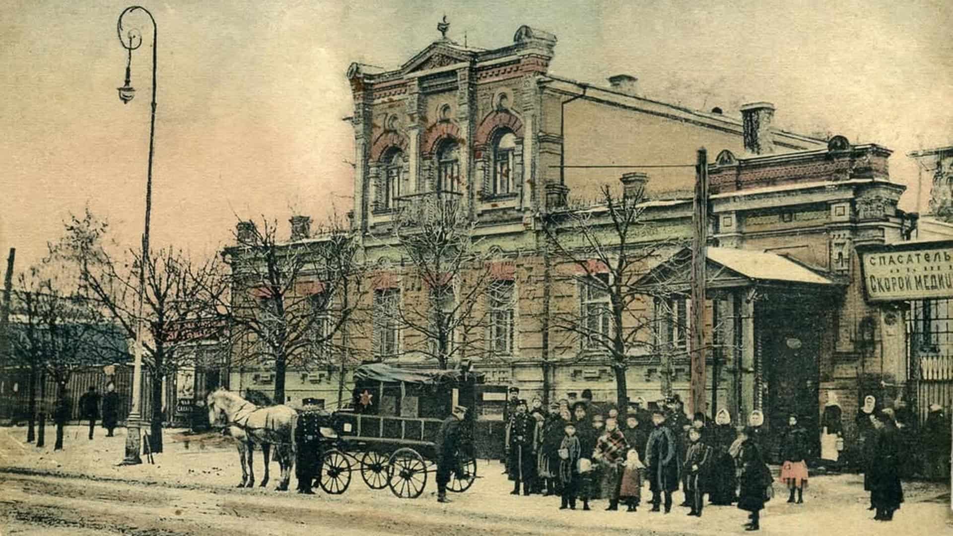 Історична листівка початку XX століття: будівля станції швидкої медичної допомоги на Володимирській, 33 у Києві, кінний екіпаж і перехожі