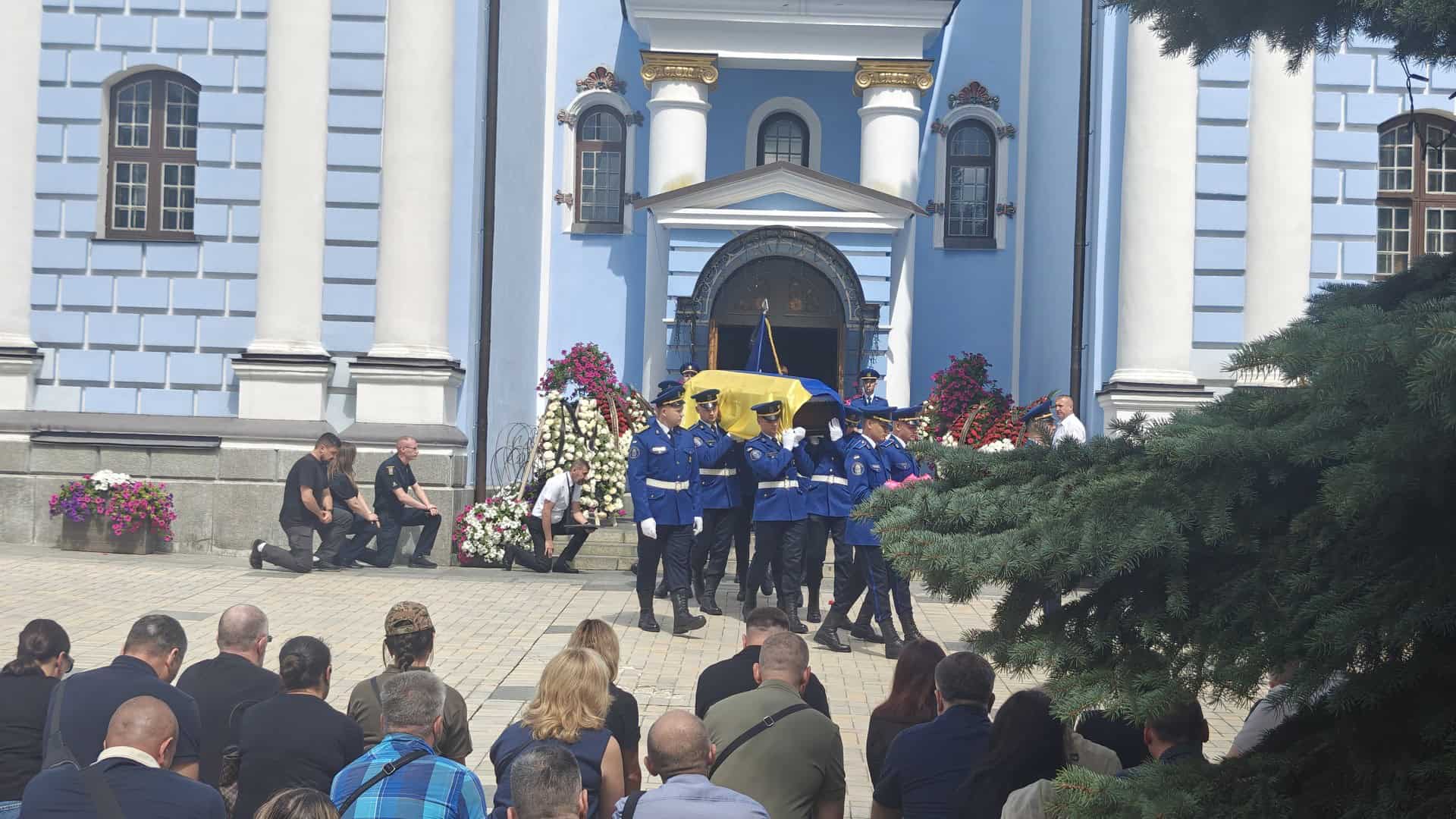 Почесна варта несе труну, вкриту прапором України, повз рідних і киян, які прийшли попрощатися, на тлі Михайлівського Золотоверхого собору