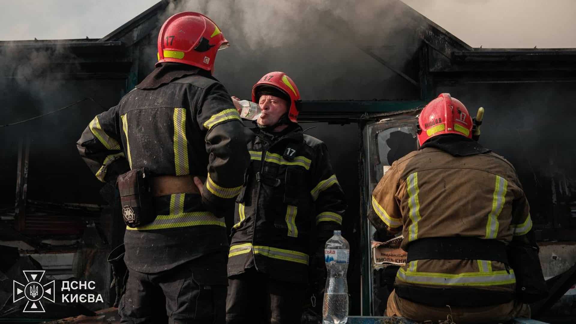 Рятувальники ДСНС Києва в димі на місці пожежі, один п’є воду з пляшки