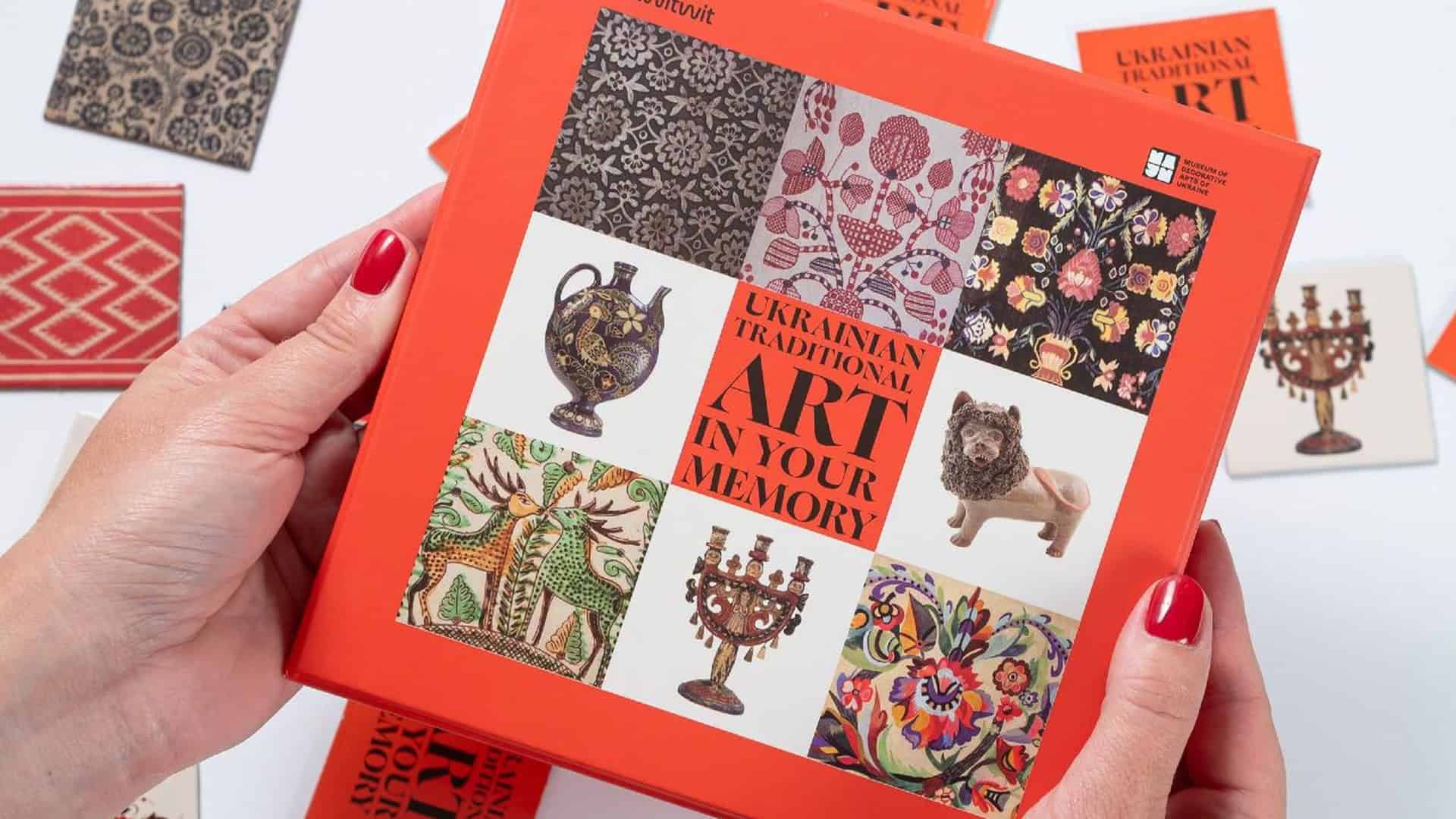 Жіночі руки тримають коробку гри-мемо Ukrainian Traditional Art In Your Memory з музейними експонатами