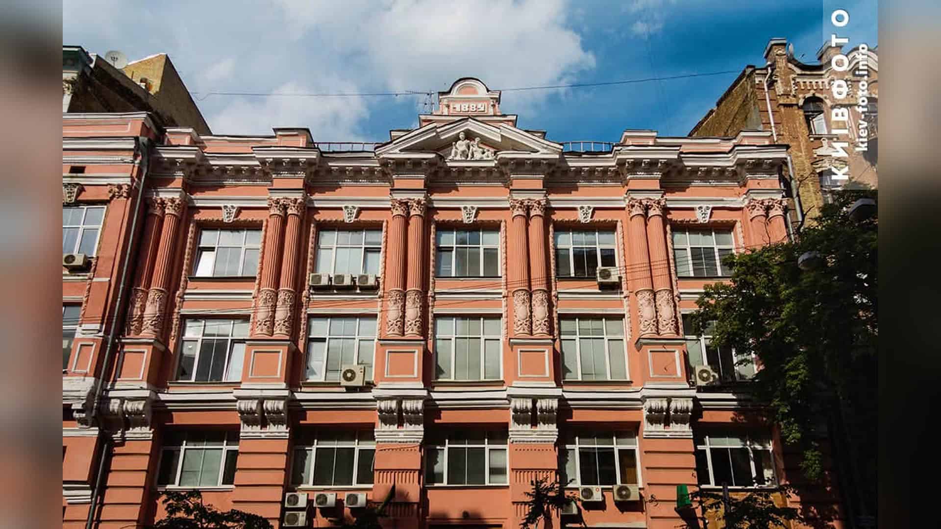 Історичний фасад будинку на вулиці Архітектора Городецького 13 у Києві зі скульптурами Меркурія та колонами коринфського ордера