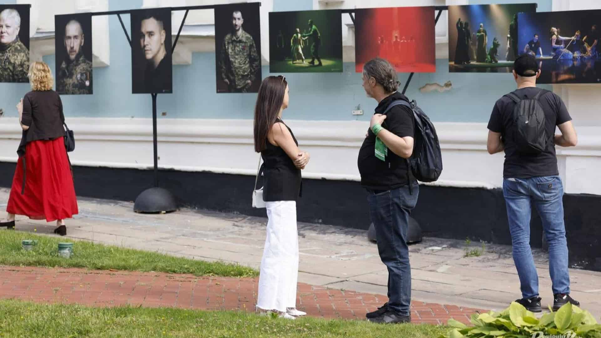 Відвідувачі розглядають портрети ветеранів на фотовиставці «Театр Ветеранів» біля Софії Київської