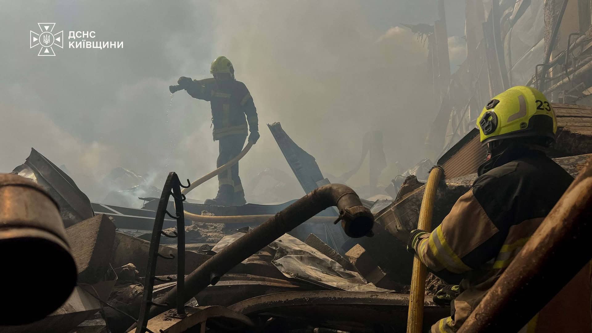 Двоє рятувальників ДСНС гасять осередки пожежі серед завалів зруйнованої конструкції на Київщині