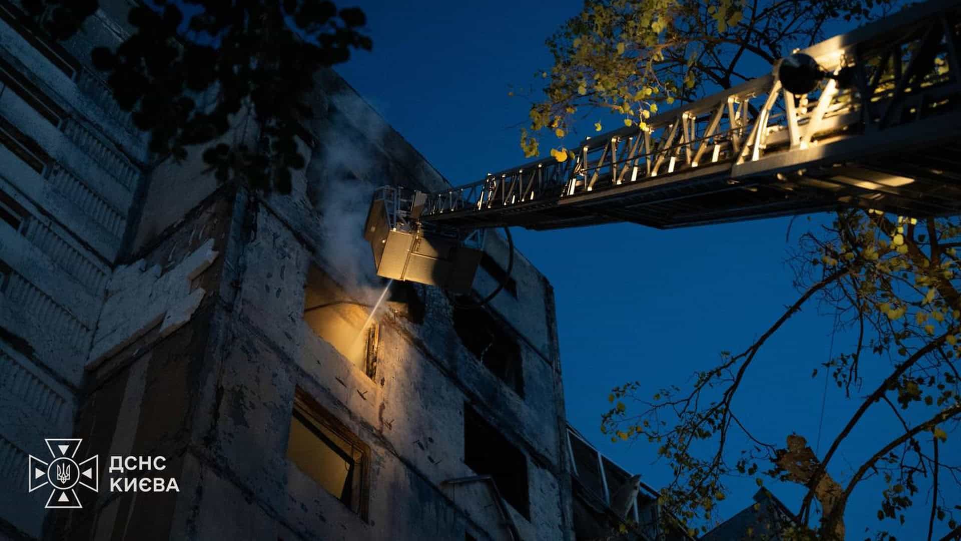 Дрон атакував будівлю телеканалу «Ми – Україна» в Києві: п’ятеро постраждалих Рятувальники ДСНС Києва гасять пожежу в багатоповерхівці за допомогою автодрабини, з вікна валить дим, знімок зроблено у сутінках