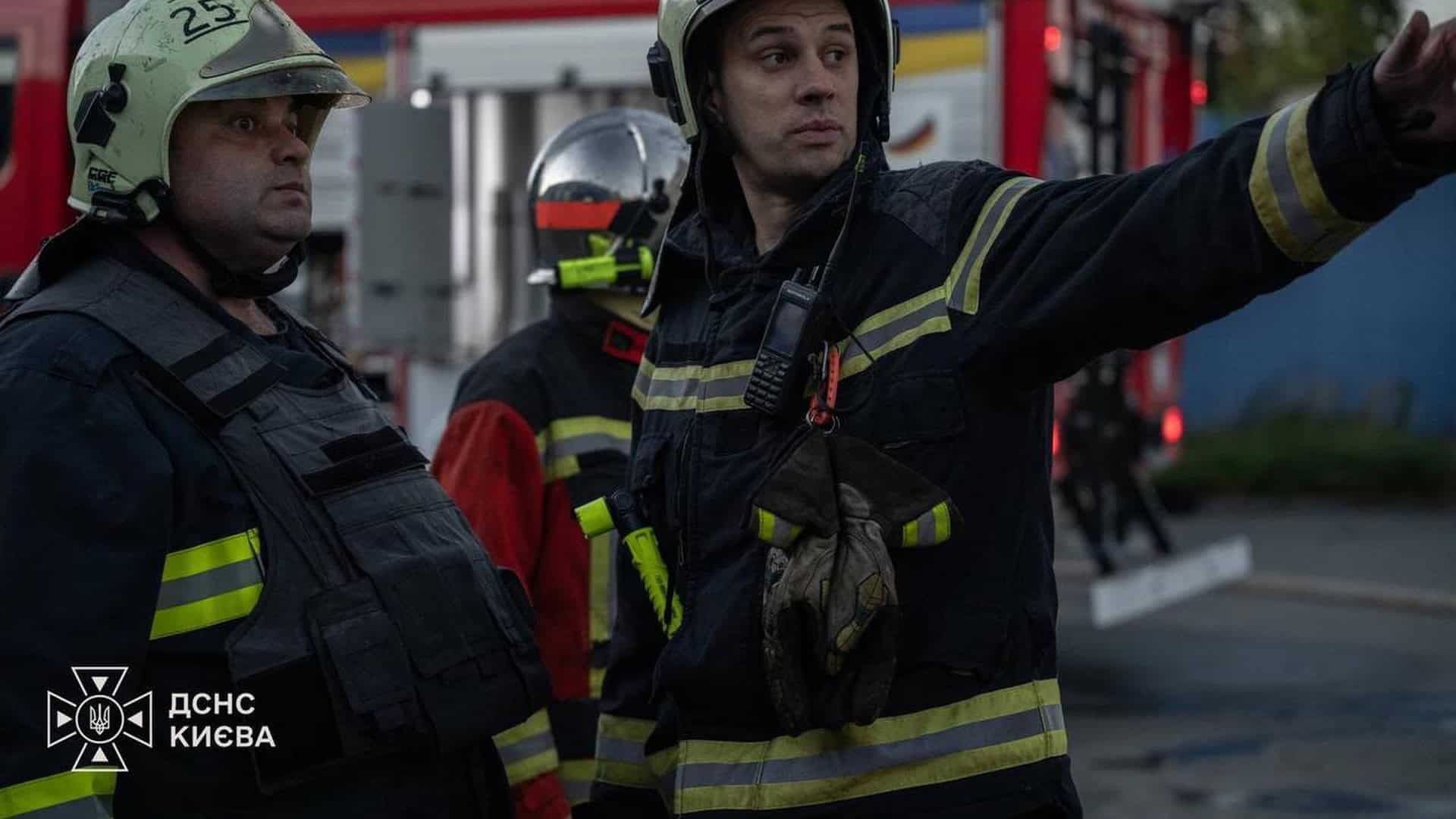 У Печерському р-ні є постраждалий після ворожої атаки — Кличко Рятувальник ДСНС Києва у захисному спорядженні показує рукою напрямок біля пожежної машини на місці ліквідації наслідків атаки