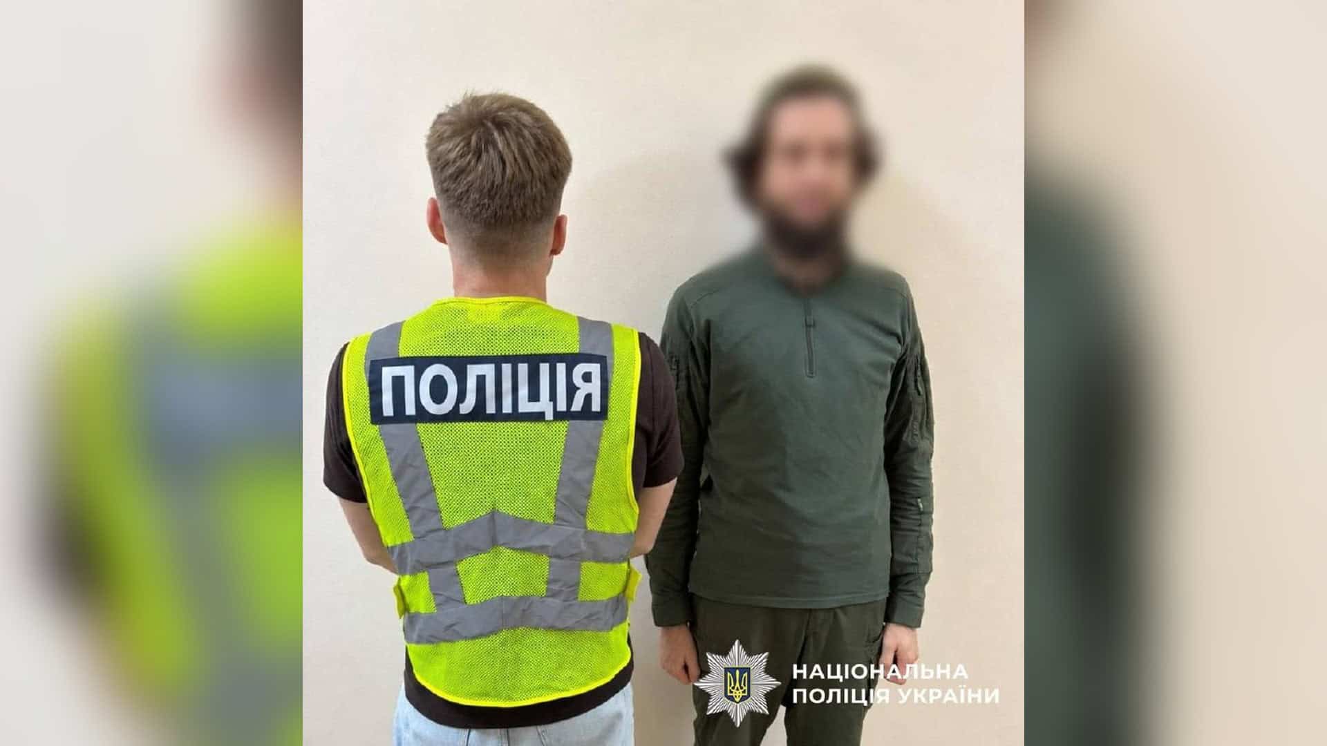Поліцейський у світловідбивному жилеті спиною до камери поруч із чоловіком із розмитим обличчям — підозрюваним у погрозах головному рабину