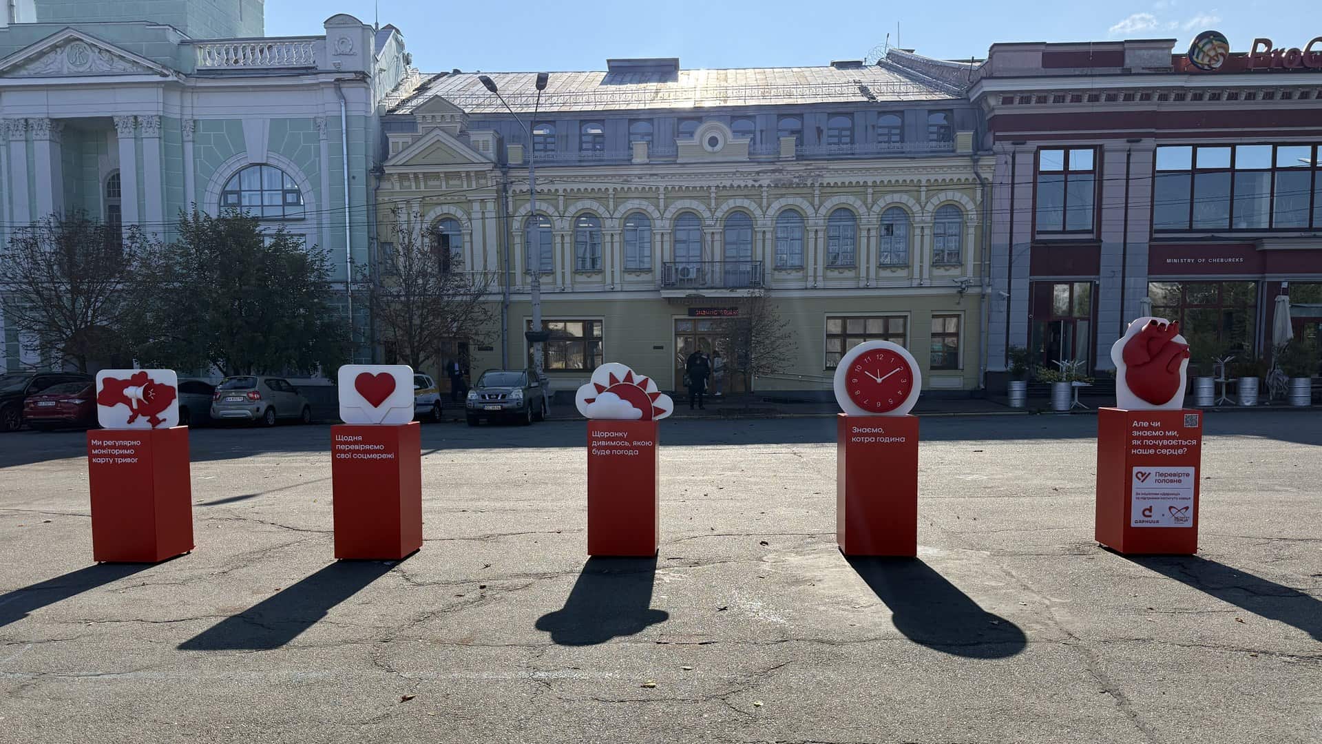 Київська психіатрична лікарня: у відділенні №19 вчать ліпити з глини Червоні тумби з символами: карта тривог, лайк, погода, годинник і серце — інсталяція на Контрактовій площі у Києві