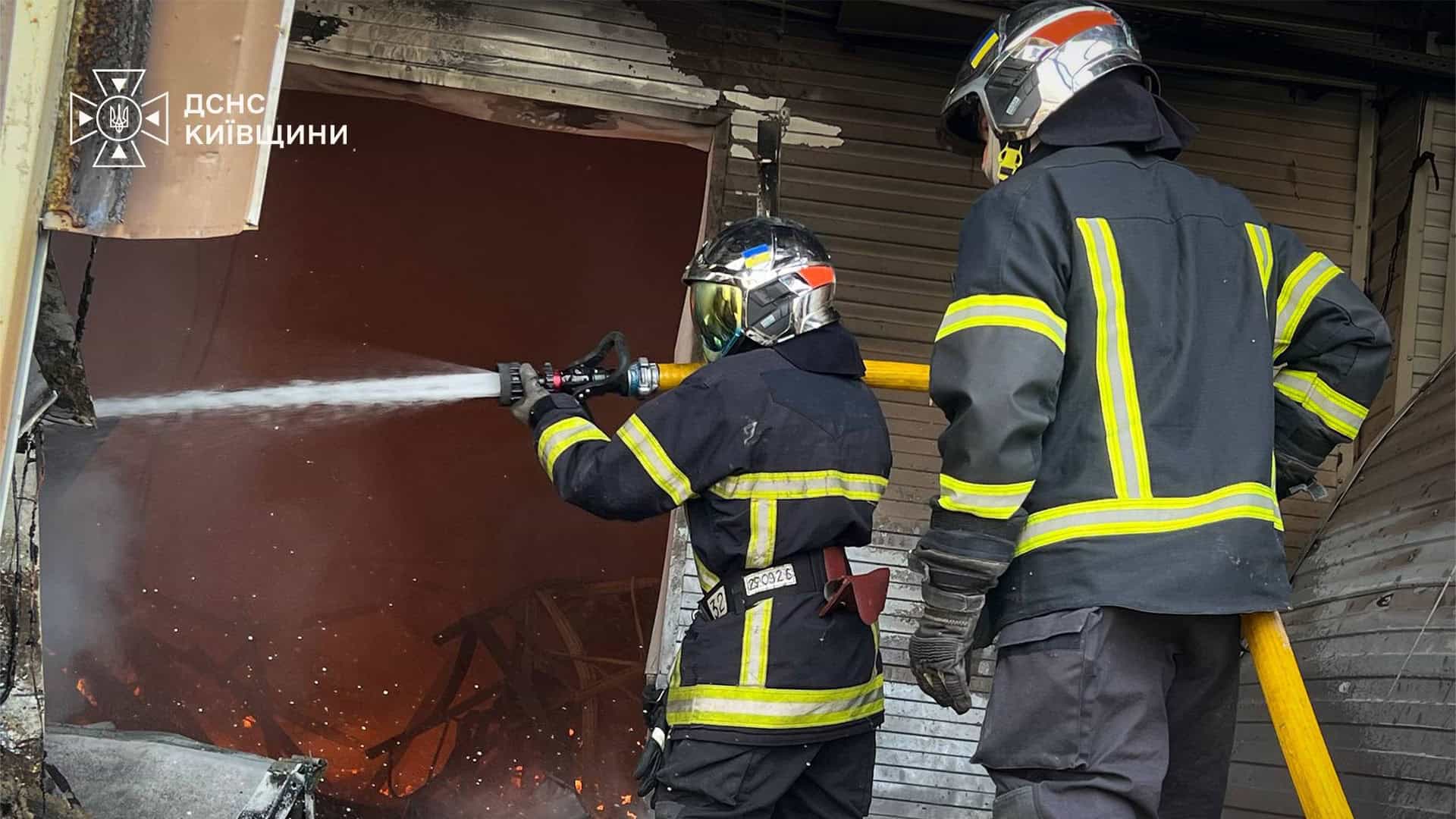 Ворог атакував 22-поверхівку у Дарницькому р-ні: п’ятеро постраждалих (оновлюється) Двоє рятувальників ДСНС Київщини подають воду через пошкоджений отвір воріт складського приміщення, всередині видно осередок займання