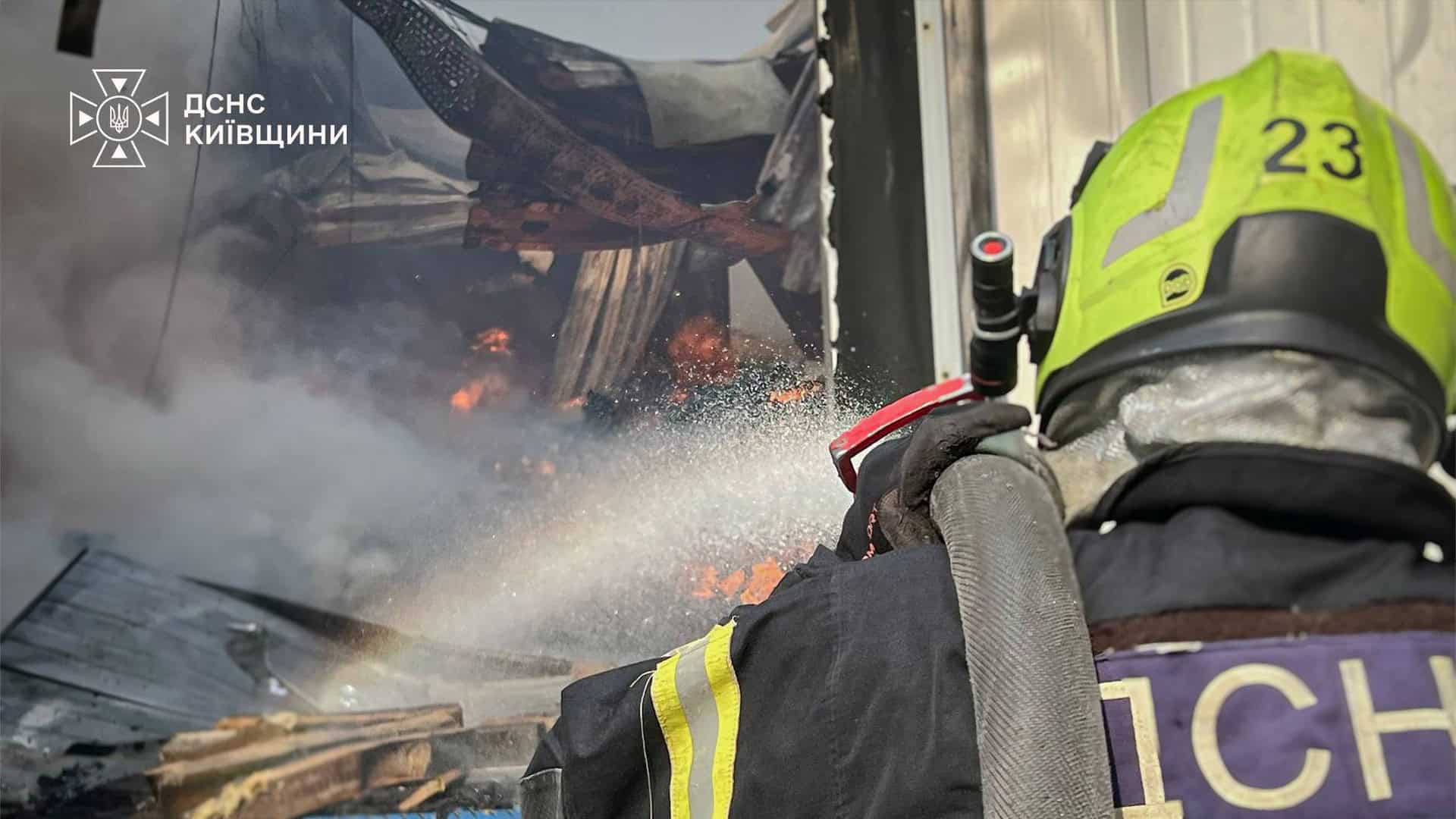 Рятувальник ДСНС крупним планом спрямовує струмінь води на палаючі конструкції всередині пошкодженого приміщення