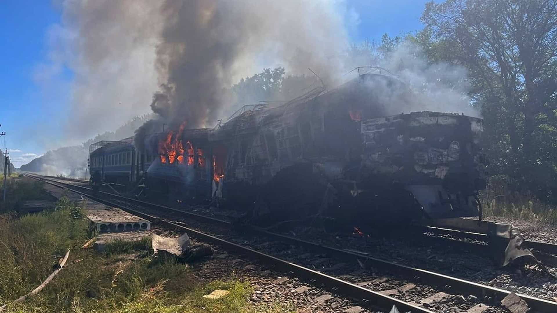 Пасажирський вагон приміського потяга охоплений полум'ям і густим чорним димом на коліях після ворожого удару по залізниці