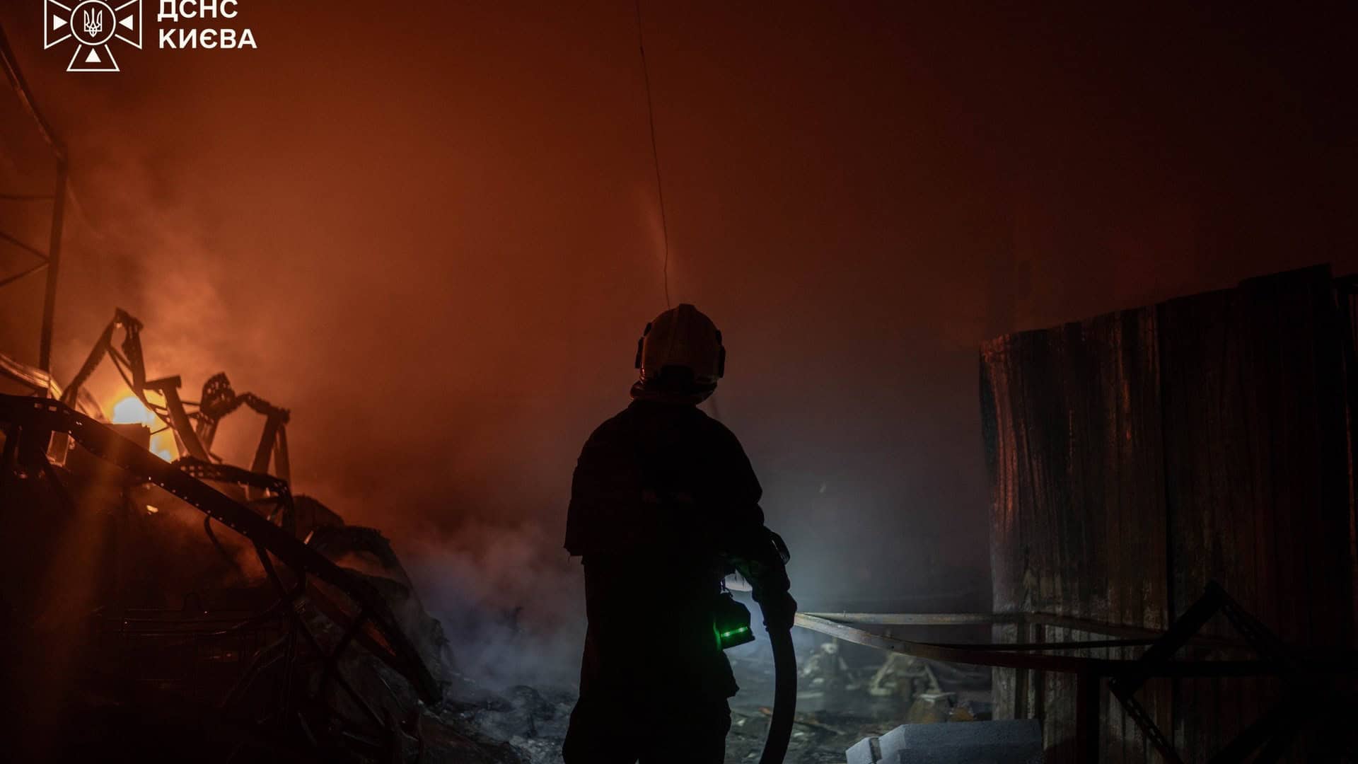 Рятувальник ДСНС Києва біля охоплених вогнем конструкцій під час гасіння пожежі в Києві після нічної атаки 30 вересня