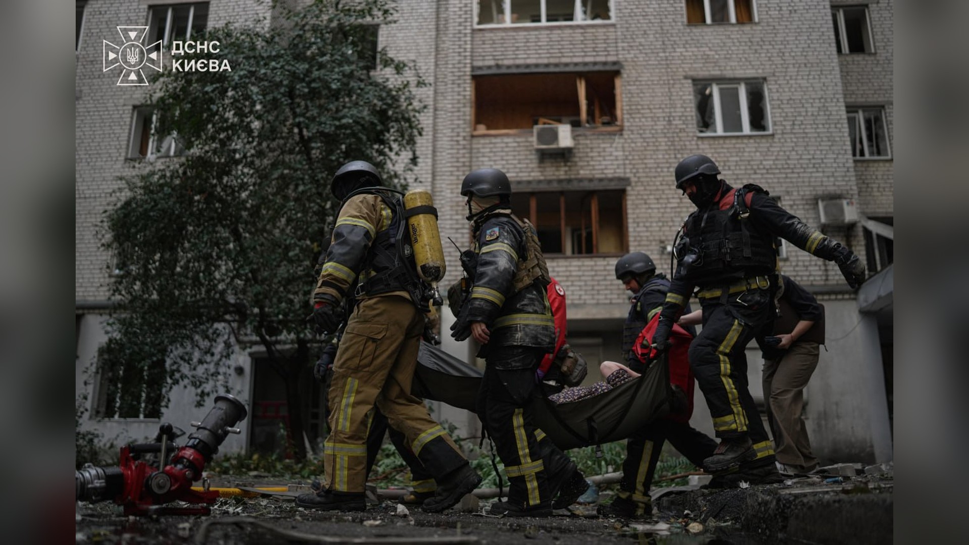 Рятувальники ДСНС виносять на ношах постраждалу від пошкодженого атакою будинку у Печерському р-ні Києва