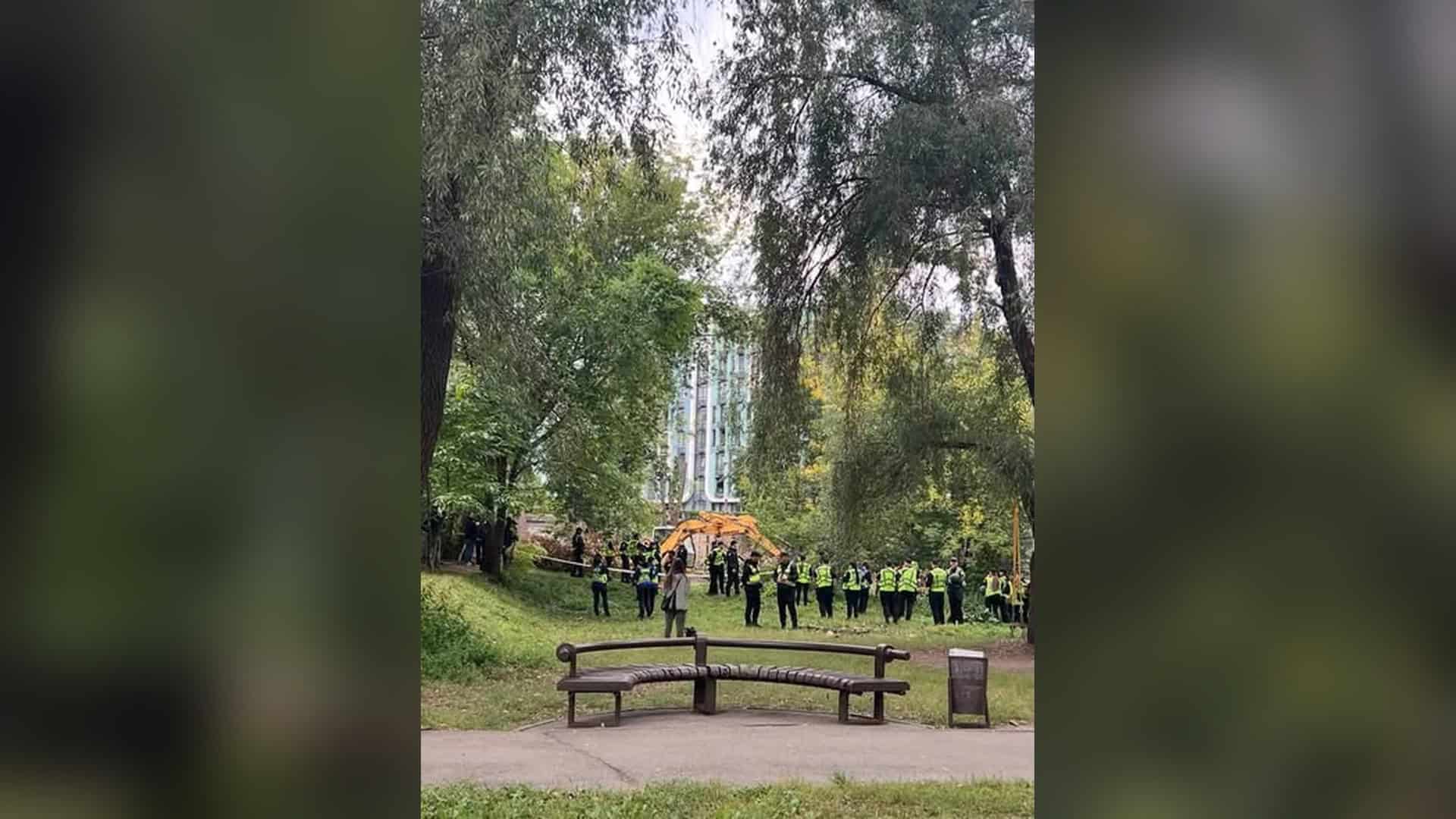 Поліцейські у світловідбивних жилетах стоять біля екскаватора в зеленій зоні на Теремках у Голосіївському р-ні Києва
