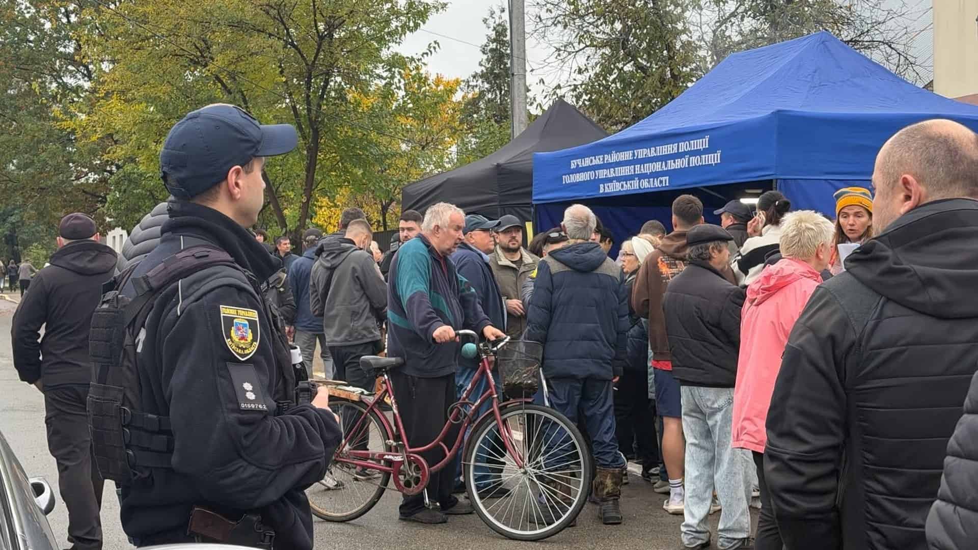 Поліцейський стоїть біля намету Бучанського районного управління поліції, де мешканці збираються після атаки на Київщину
