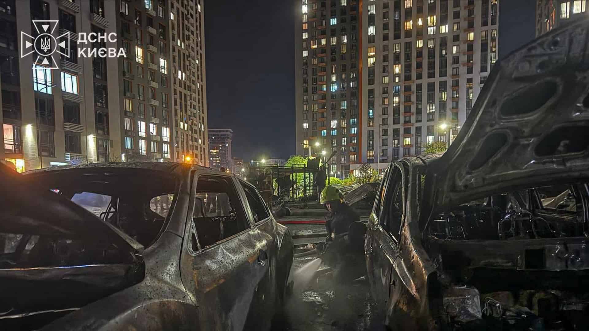 У Дарницькому р-ні уламки БпЛА пошкодили будинок, постраждала жінка (оновлено) Рятувальник ДСНС заливає водою спалені автівки у дворі багатоповерхівок у Дарницькому р-ні Києва після удару БпЛА
