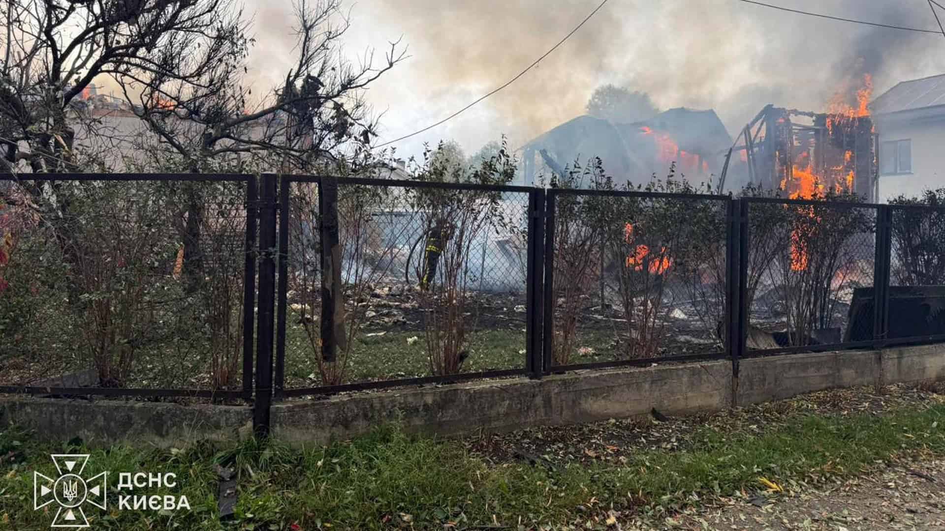 Атака на Київщину: загинула людина, 2 постраждалих на Фастівщині й Бучанщині Палаючі приватні будинки за парканом у Дарницькому р-ні Києва, рятувальник ДСНС працює у дворі серед диму після атаки 12 жовтня