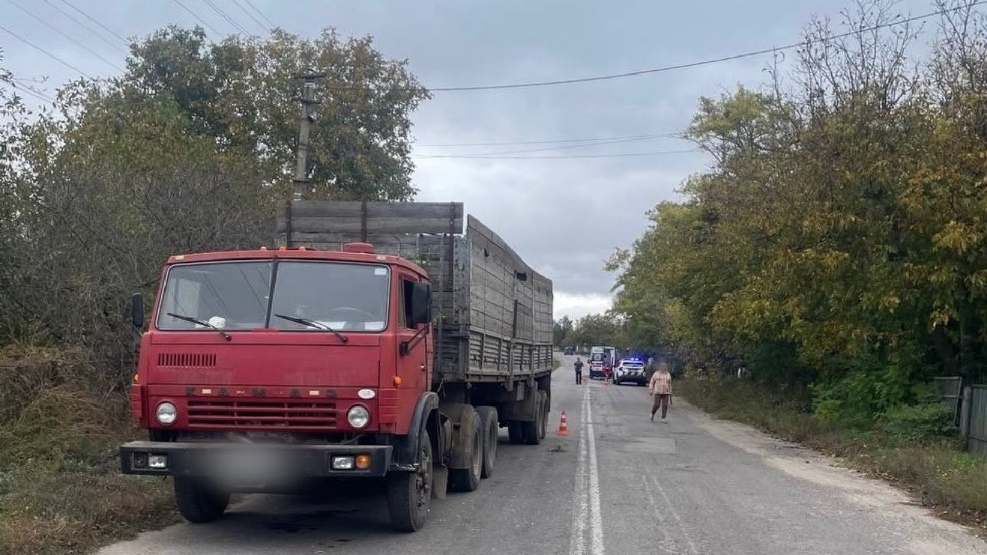 Червона вантажівка Камаз на узбіччі сільської дороги, позаду поліцейське авто і швидка на місці ДТП у Городищі-Пустоварівському