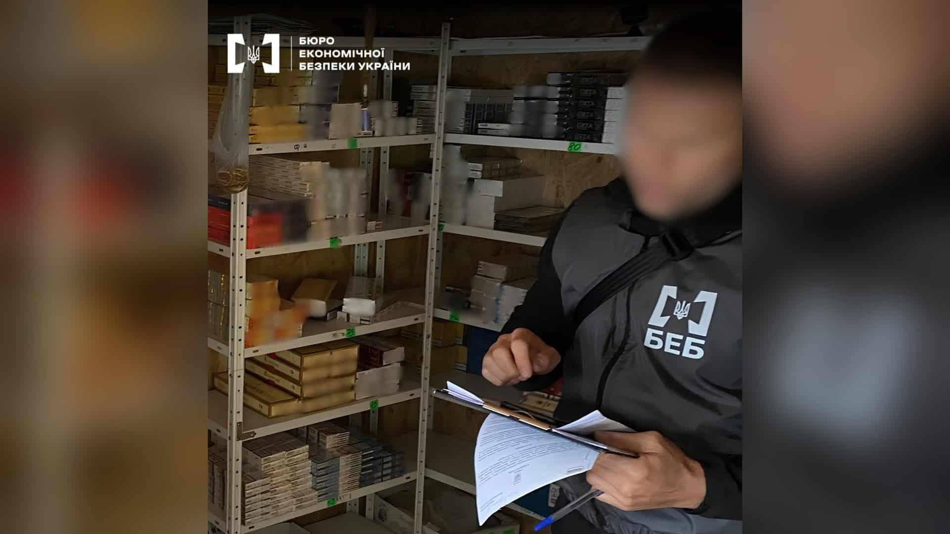 Детектив БЕБ із документами біля стелажів із пачками сигарет у торговельній точці на Київщині