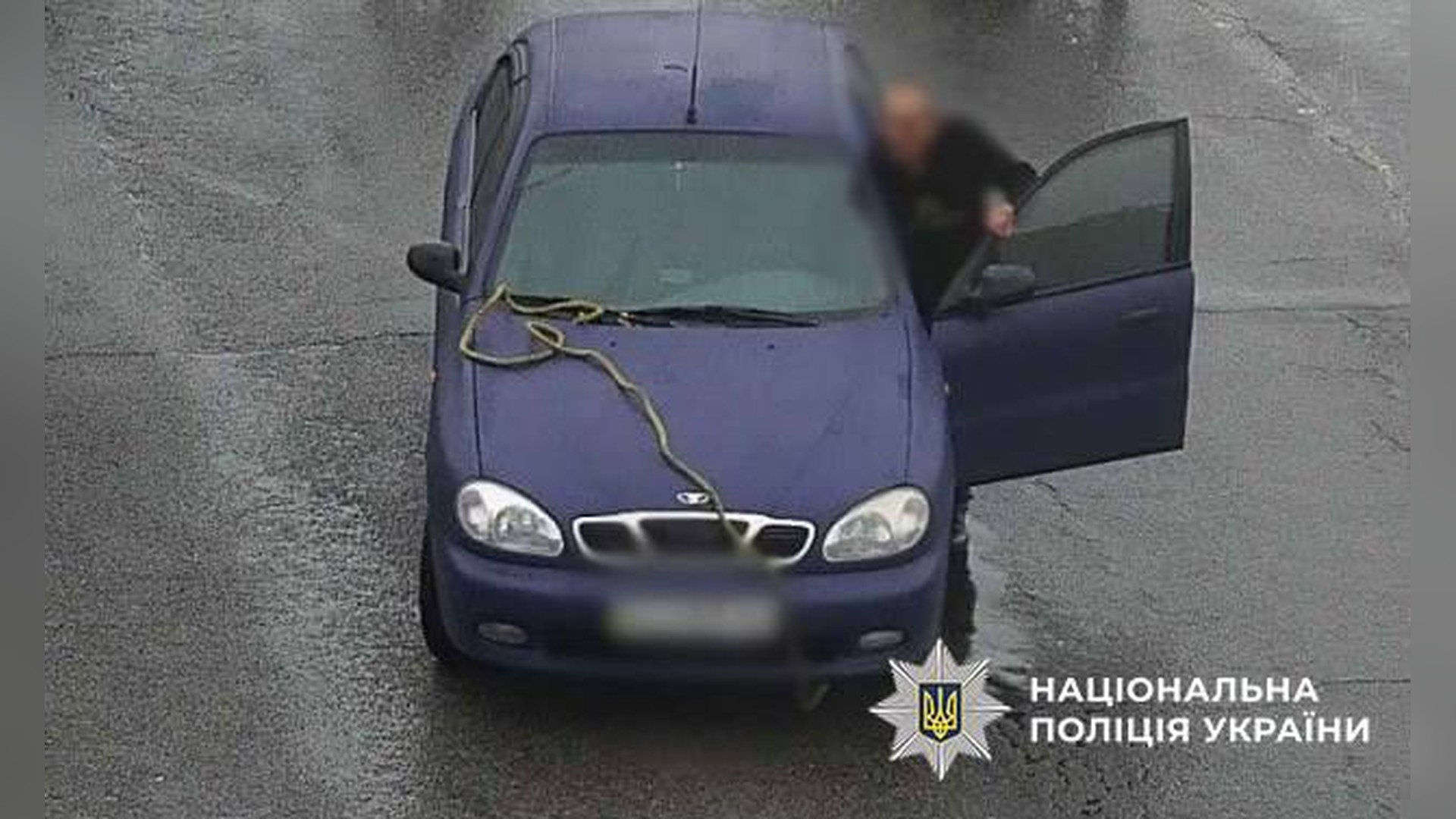 Дитсадок № 585 в Оболонському р-ні 8 місяців без укриття через брак коштів Чоловік біля автомобіля Daewoo Lanos з тросом на капоті на кадрі камери спостереження в Деснянському р-ні Києва