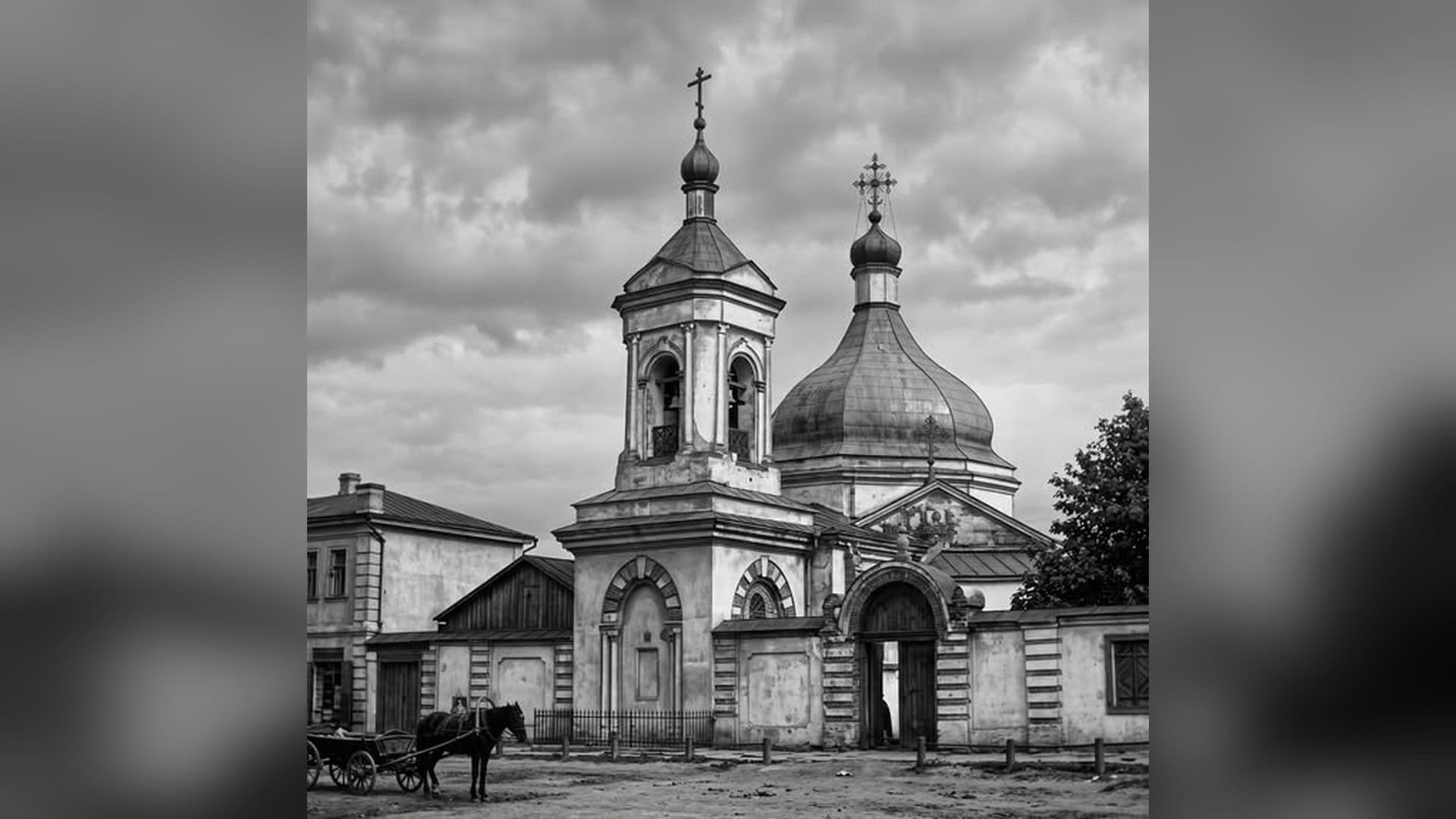 Архівне чорно-біле фото київської церкви з дзвіницею, куполом і брамою, на площі перед нею кінь із возом