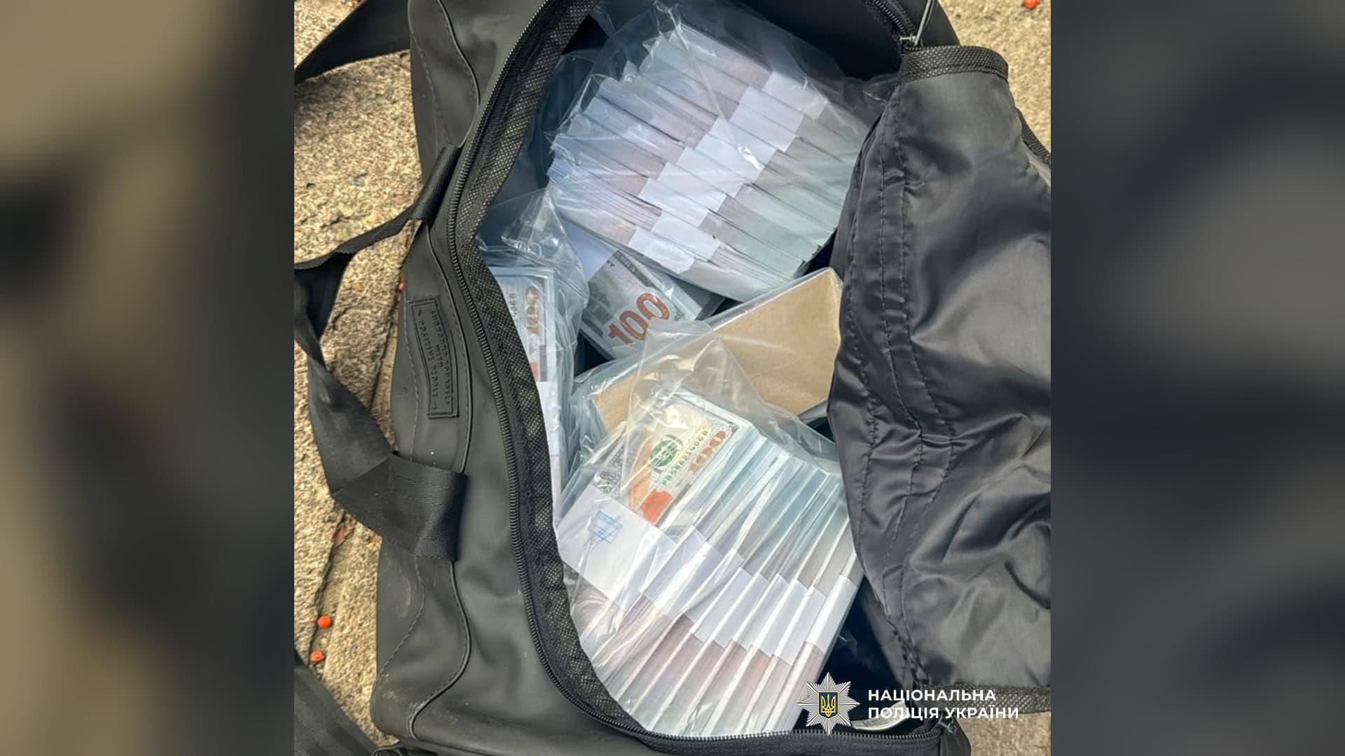Відкрита чорна сумка з пачками доларів у прозорих пакетах, вилучена у справі про спробу крадіжки 5 млн доларів