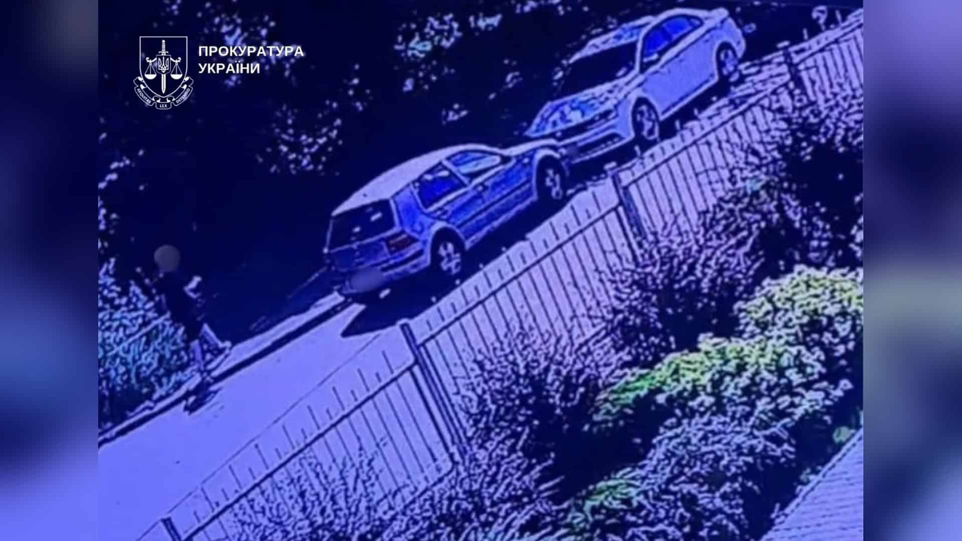 Двоє чоловіків стоять біля поліцейського авто в Солом'янському р-ні Києва після затримання за пособництво шахрайству на 2,8 млн грн