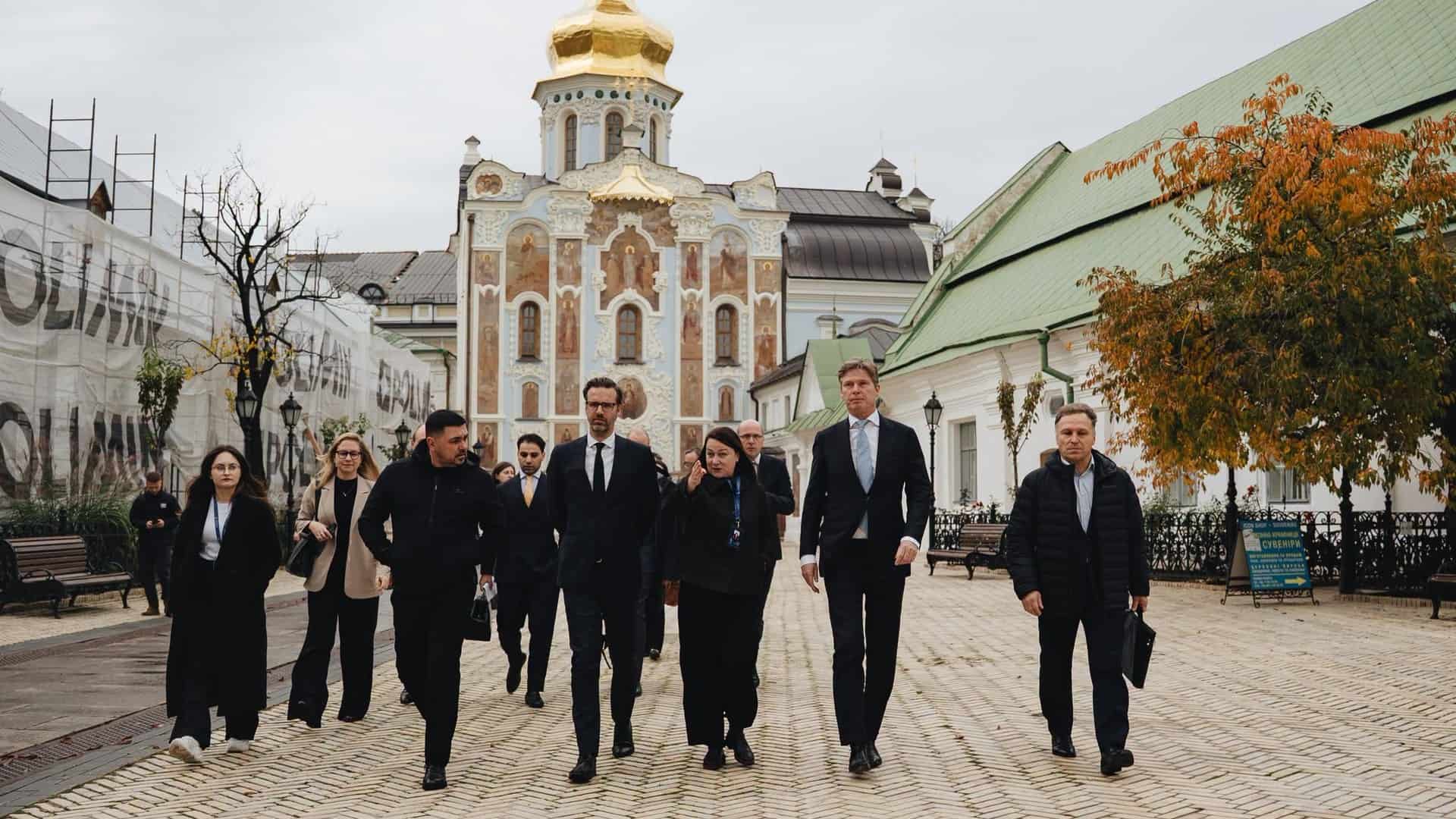 Делегація Нідерландів разом із представниками заповідника йде територією Києво-Печерської лаври на тлі Троїцької надбрамної церкви