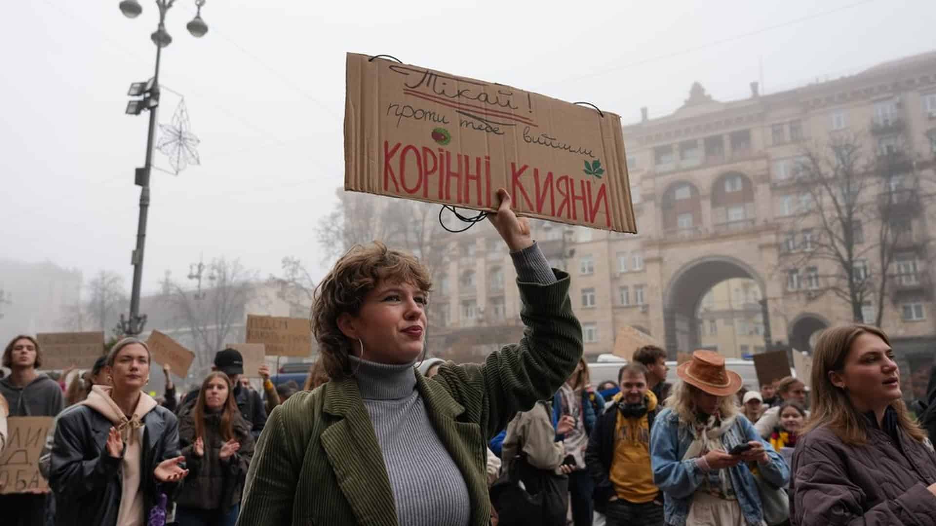 Суд щодо заказника «Осокорківські луки»: засідання 19 жовтня о 16:00 Учасниця мітингу під КМДА на Хрещатику тримає картонний плакат «Корінні кияни», позаду натовп протестувальників
