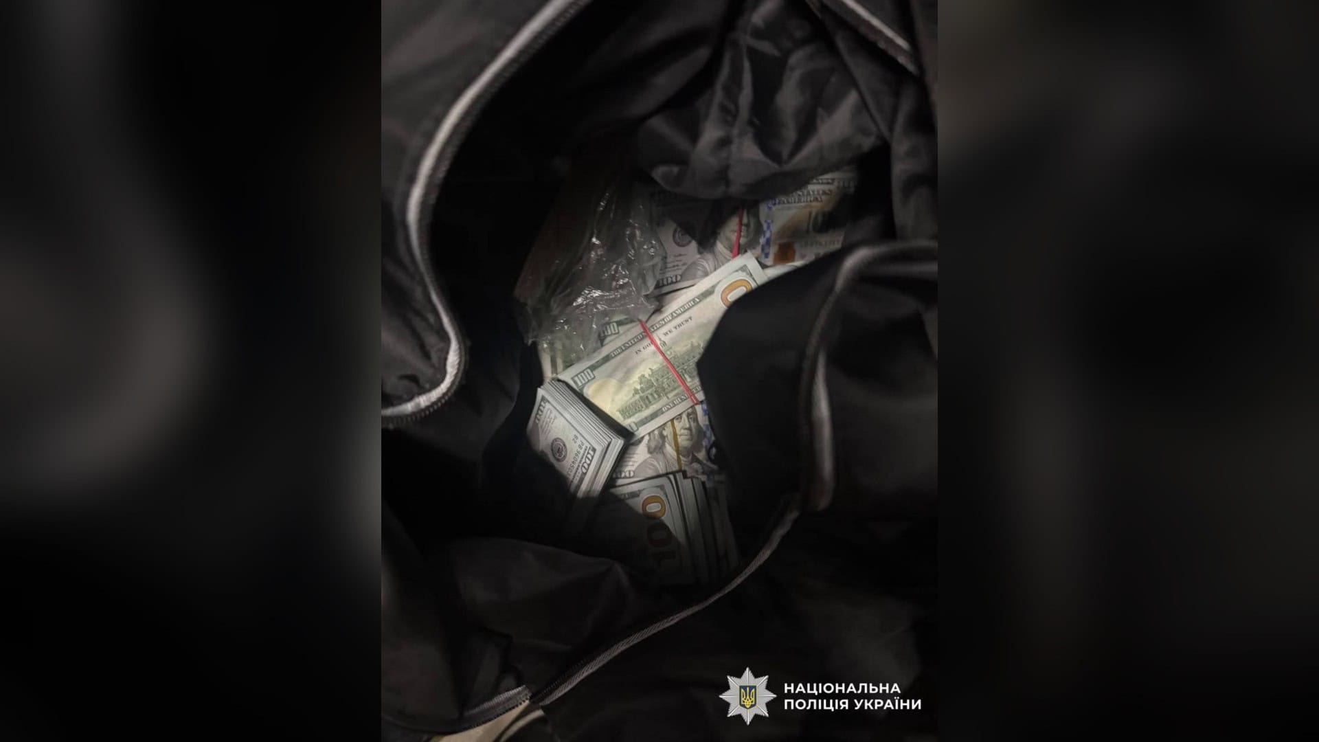 У Києві судитимуть трьох іноземців за напад і пограбування в Гідропарку Відкрита чорна спортивна сумка з пачками стодоларових купюр на фото Національної поліції України