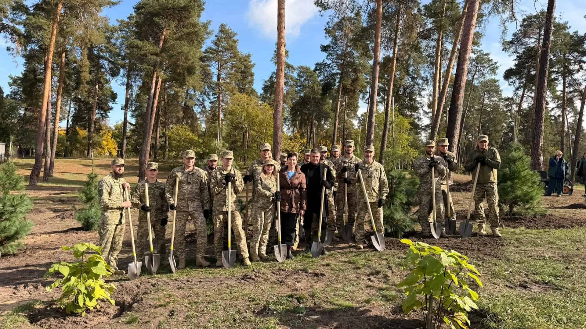 Військові, працівники КП і посадовці з лопатами після висадки молодих сосен у парку «Партизанська слава» в Дарницькому р-ні