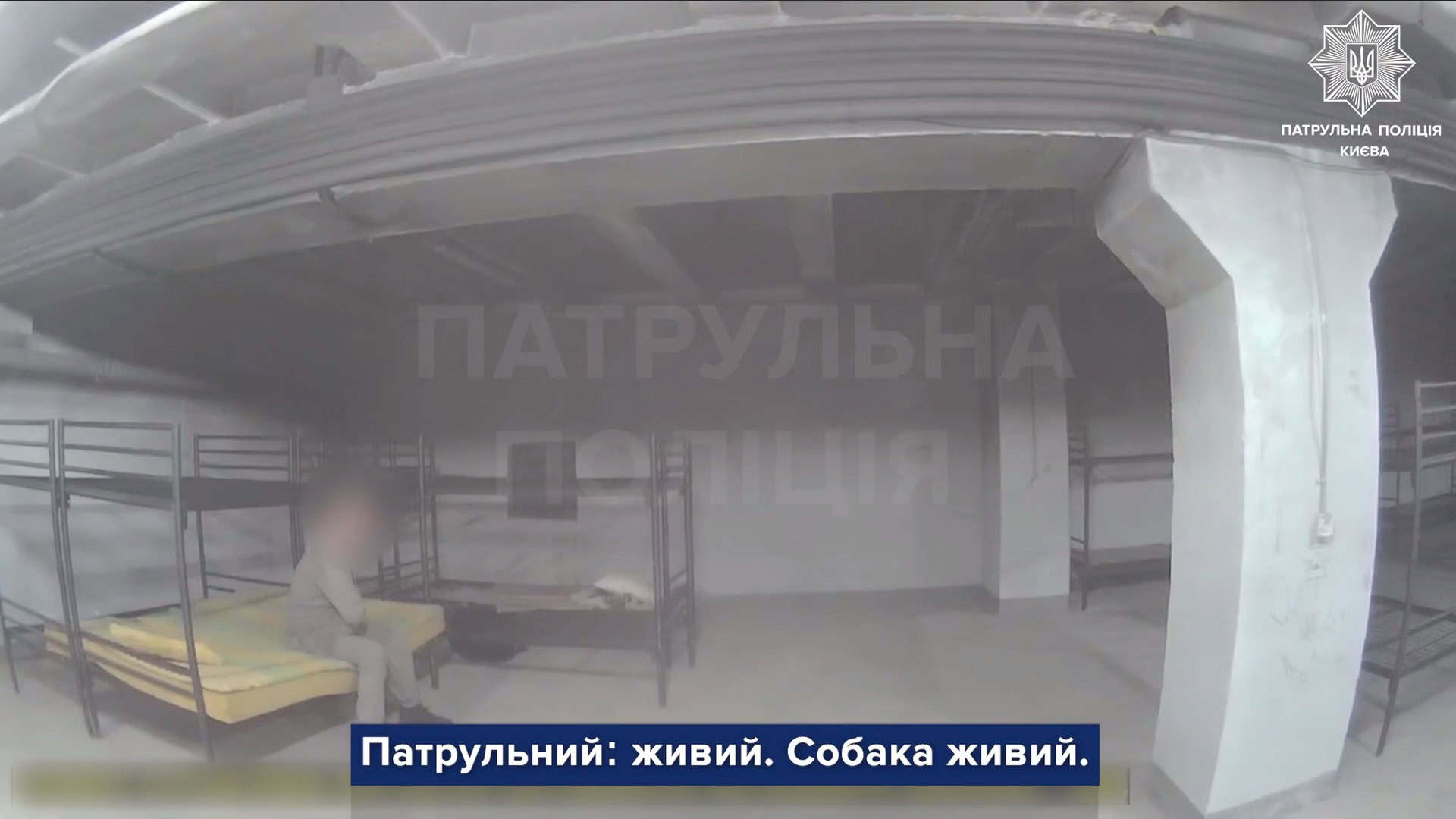 Пожежа на вул. Луцькій у Подільському р-ні — рятувальники врятували жінку Чоловік із розмитим обличчям сидить на нарах в укритті житлового будинку, кадр відео патрульної поліції Києва із субтитрами