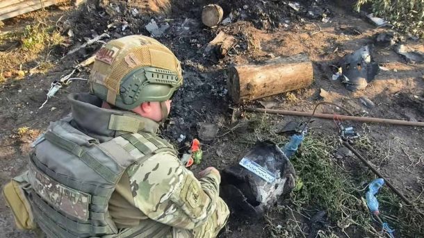 Вибухотехнік поліції Київщини оглядає бойову частину російського безпілотника на подвір’ї приватного будинку на Бориспільщині