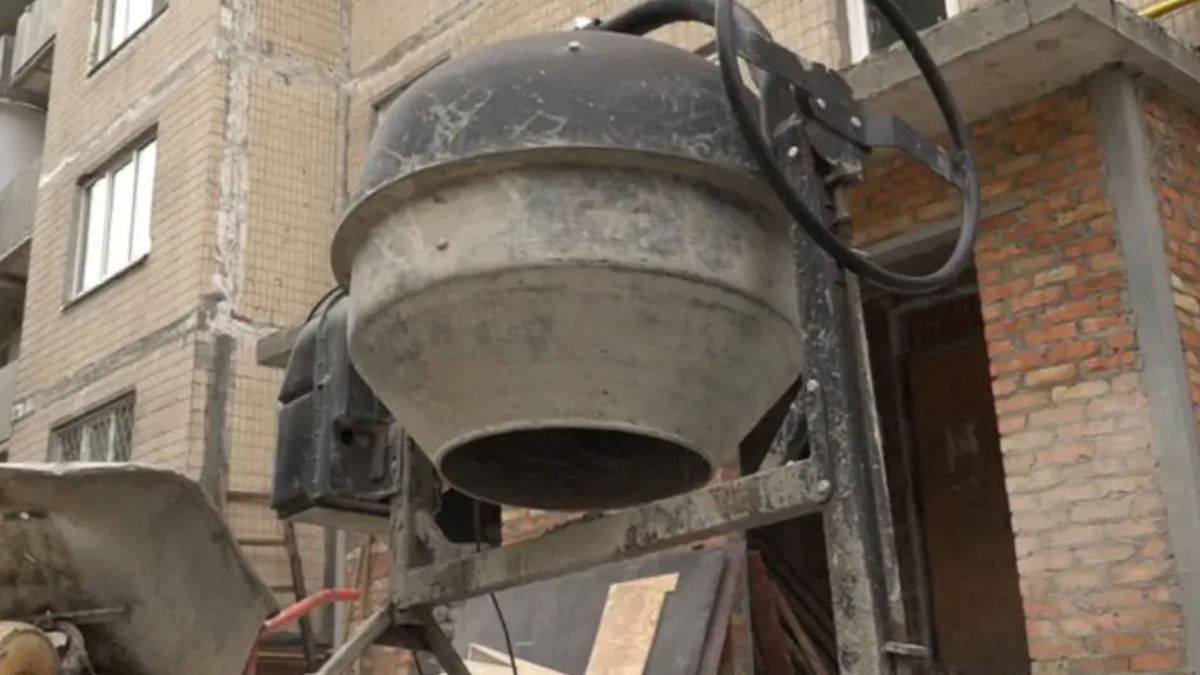 Бетономішалка та будівельне обладнання біля пошкодженої цегляної багатоповерхівки під час відновлювальних робіт після обстрілів у Солом'янському районі Києва