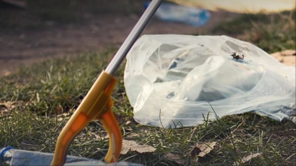 Інструмент для прибирання та пакет зі сміттям на газоні під час весняного двомісячника з благоустрою у Києві