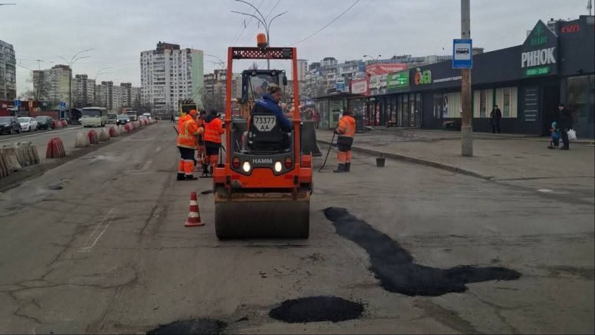 Дорожня техніка та робітники у помаранчевих жилетах ремонтують аварійні ділянки дорожнього покриття на вулиці Хрещатик у Києві