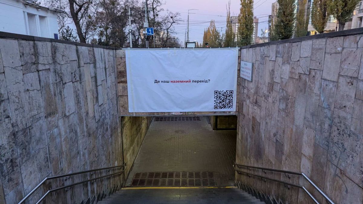 Вхід до підземного переходу з банером: «Де наш наземний перехід?» та QR-кодом