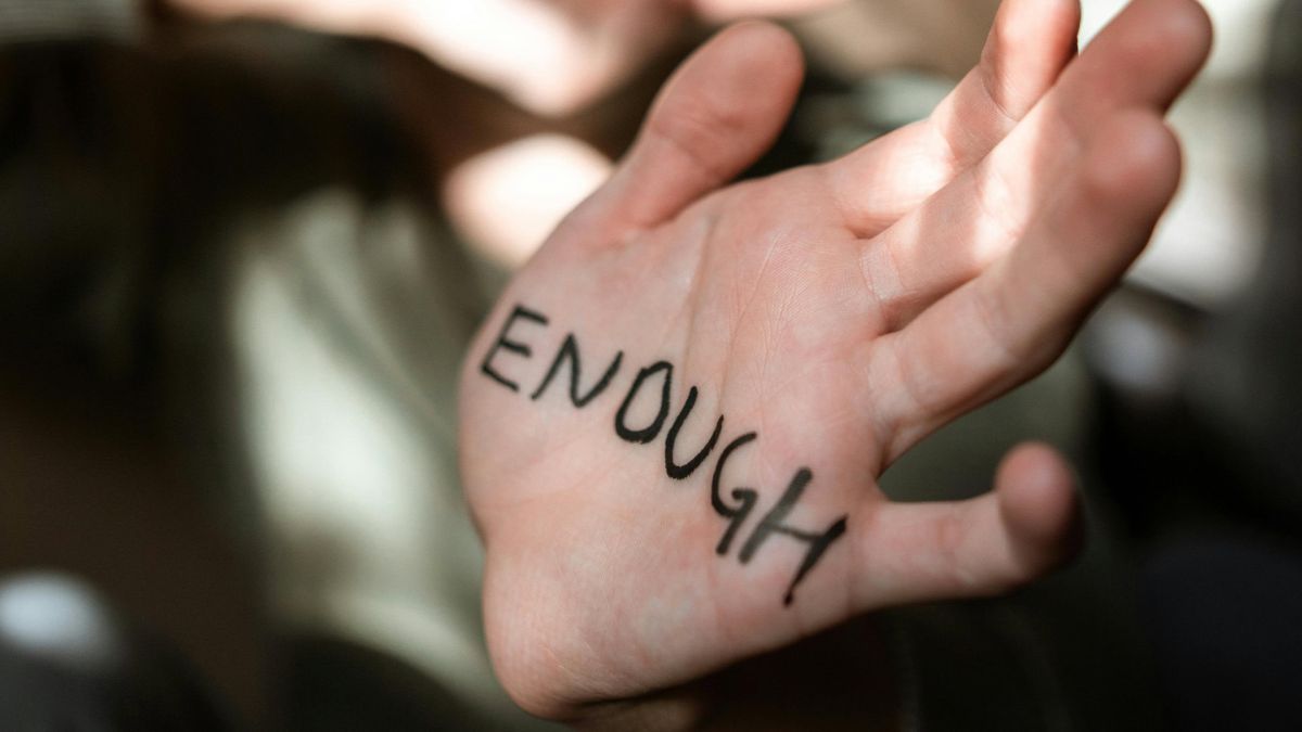 Символічне зображення боротьби із насильством — рука з написом Досить англійською мовою