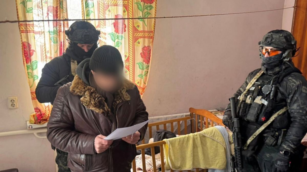 Співробітники поліції у спецекіпіровці вручають підозру затриманому у справі про незаконний продаж трофейної зброї на Київщині