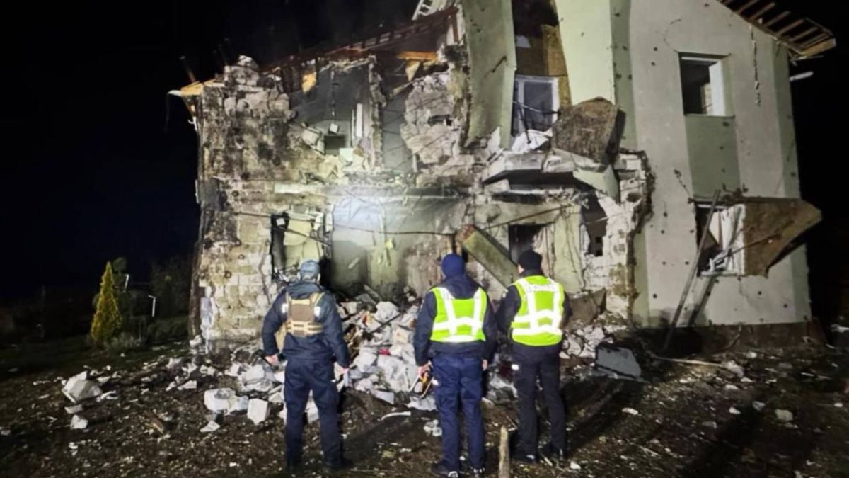 Зруйнований будинок в Київській області, троє поліцейських стоять і дивляться на нього в темноті