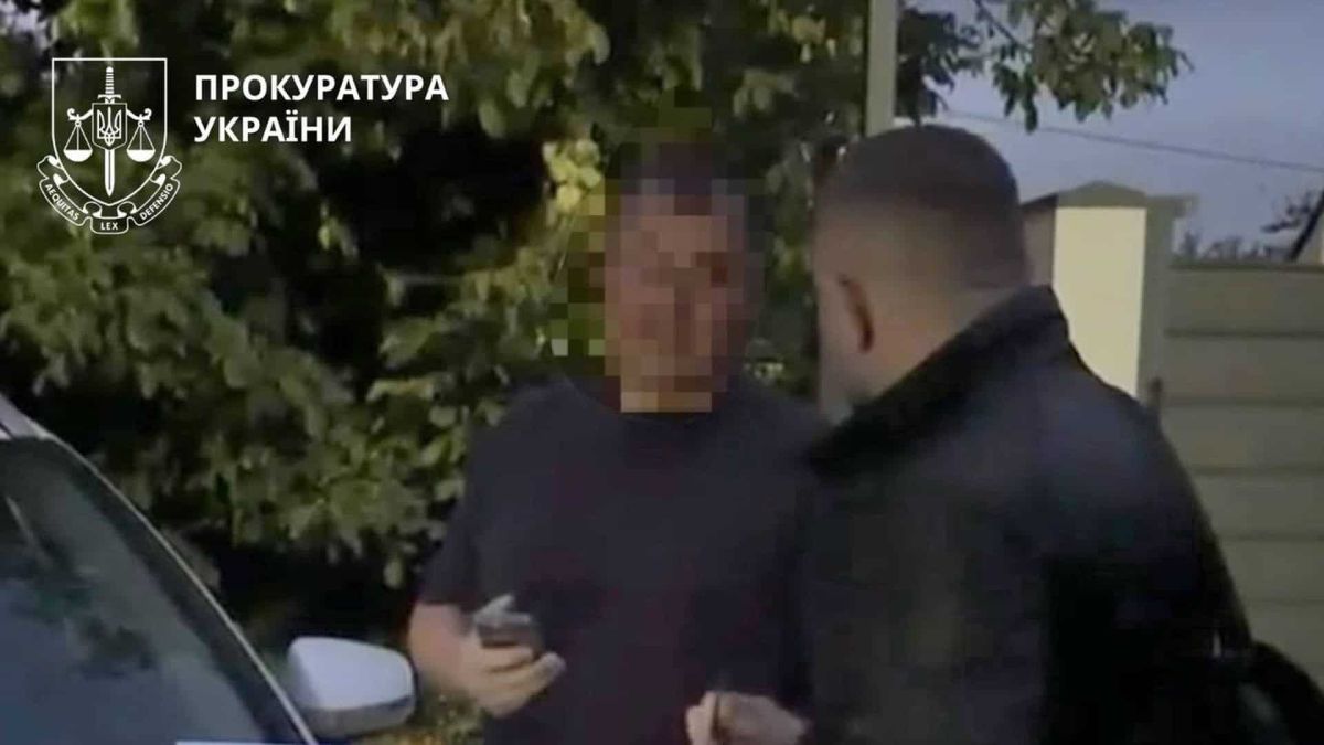 Директора ТОВ підозрюють у продажу 15 авто, ввезених як допомога для ЗСУ Правоохоронець розмовляє з чоловіком із розмитим обличчям біля автомобіля під час повідомлення про підозру