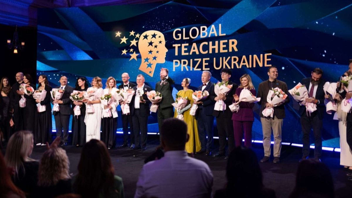 На сцені стоять близько двадцяти людей з квітами, яких нагородили премією «Кращий вчитель року»