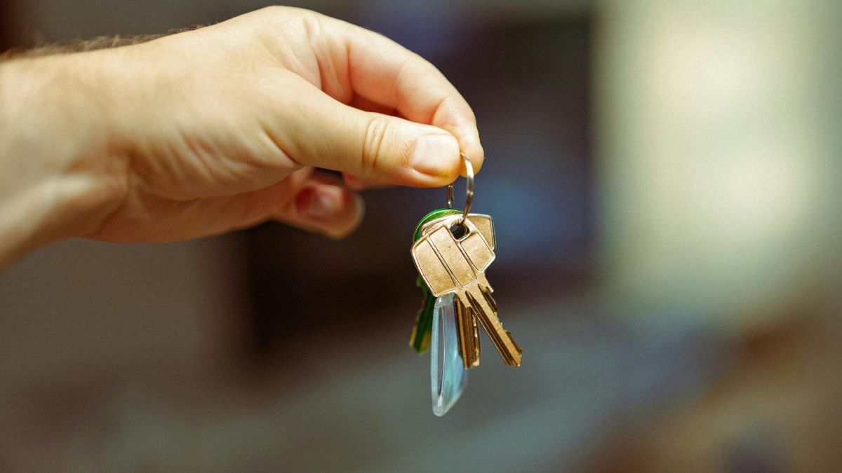 Рука тримає ключі від квартири на розмитому фоні