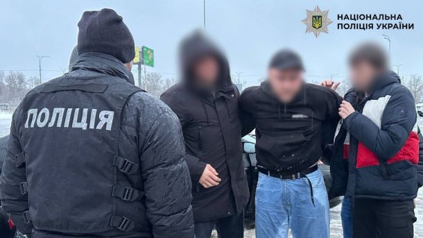 Підозрюваний із заламаними руками, якого тримають правоохоронці в цивільному