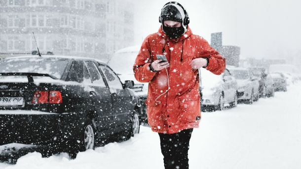 В Обухові жінка збувала метадон з держпрограми: їй загрожує до 10 років Людина у червоній куртці та навушниках іде засніженим тротуаром повз запарковані автомобілі під час сильного снігопаду