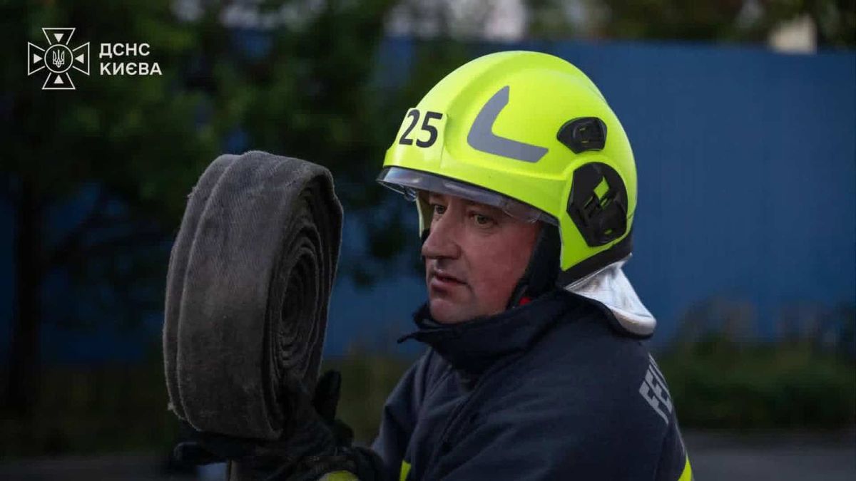 Рятувальник ДСНС Києва у жовтому шоломі тримає скручений пожежний рукав на місці ліквідації наслідків атаки