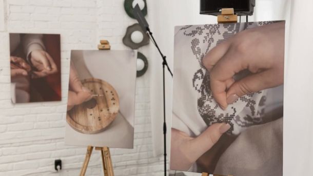 Експозиція виставки «(Не) видимі жінки» — фотографії жіночих рук за рукоділлям на мольбертах у виставковому просторі