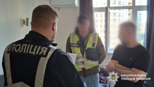 Двоє працівників поліції стоять в кімнаті та спілкуються з чоловіком, якому вручають підозру
