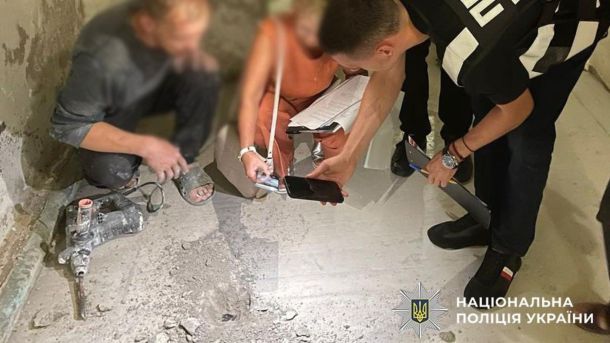 Двоє осіб фотографують бетонну підлогу в укритті
