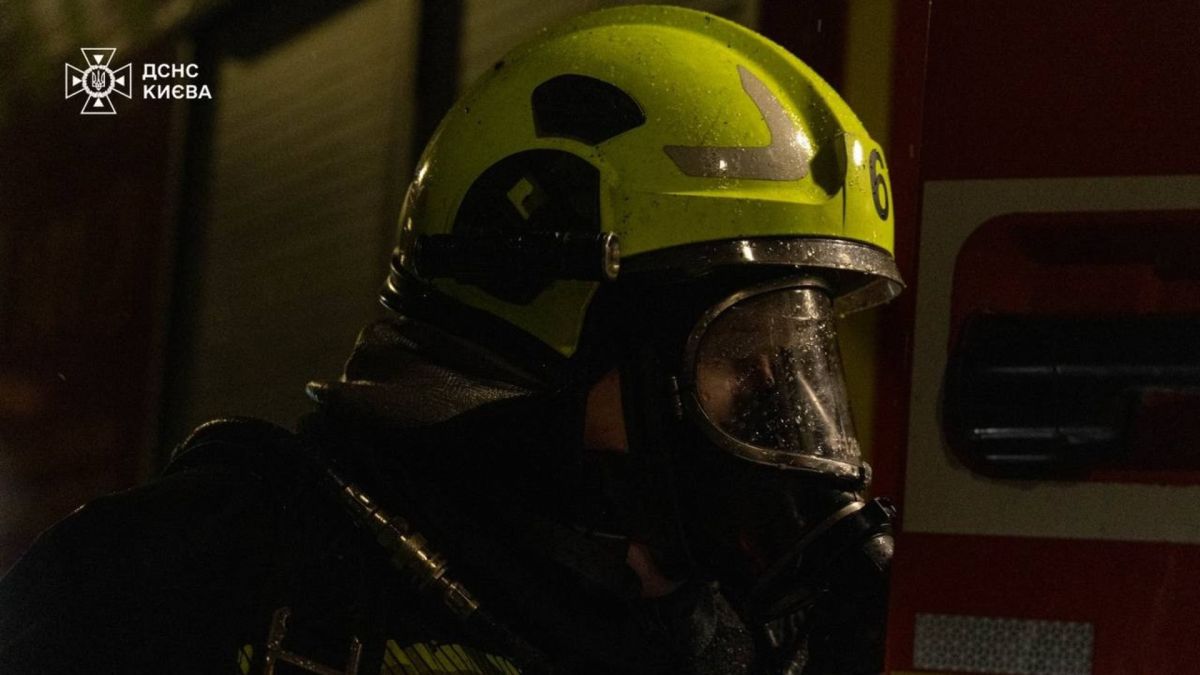 Пожежник ДСНС у захисному шоломі та дихальному апараті-протигазі на місці пожежі в Києві вночі